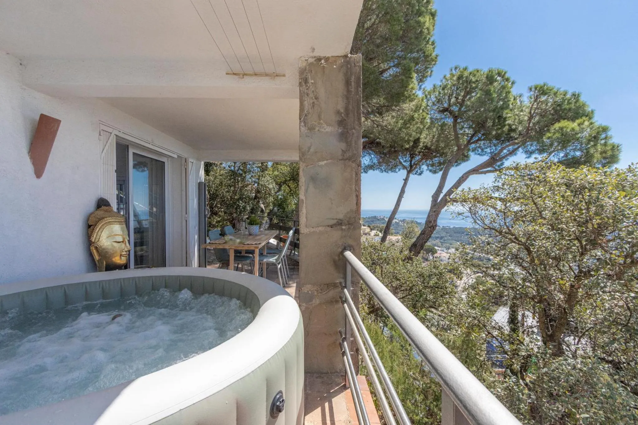 Terrasse avec jacuzzi et vue sur la mer et la végétation.