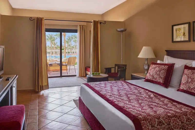Chambre lumineuse avec un lit double donnant sur une terrasse et une piscine.