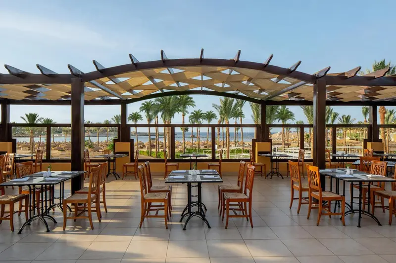 Une salle à manger lumineuse s'ouvre sur une vue de palmiers et de mer.