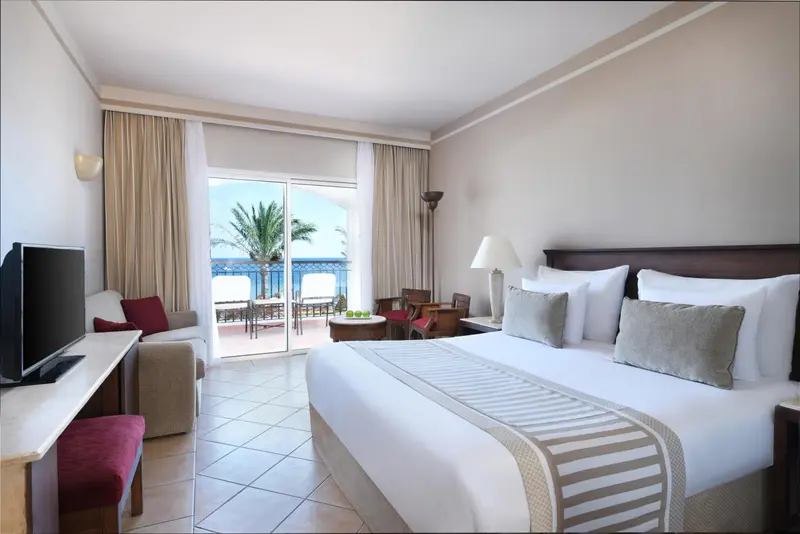 Une chambre lumineuse s'ouvre sur une terrasse avec vue sur la mer.