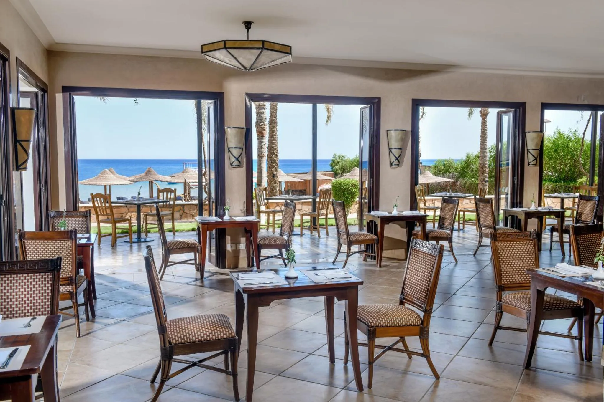 Une salle lumineuse s'ouvre sur une vue de palmiers et de mer.