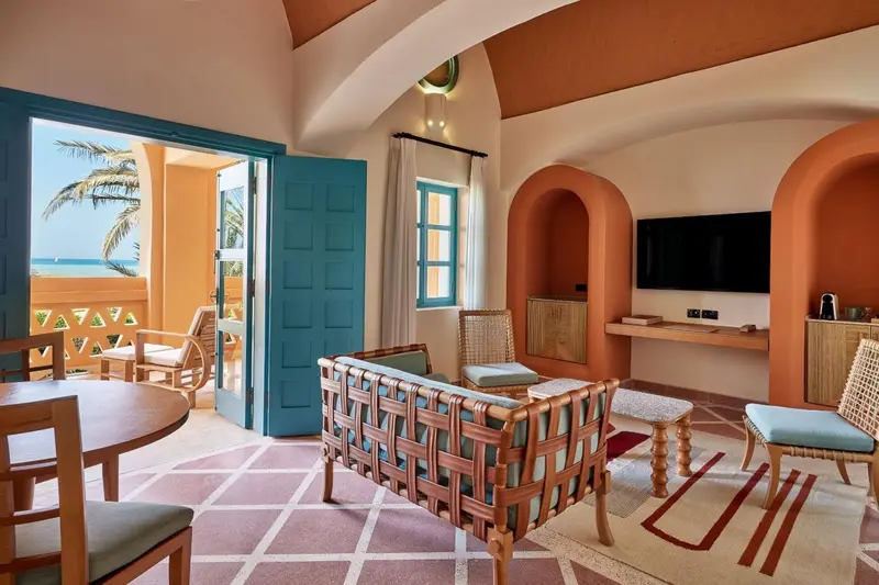 Espace de vie intérieur lumineux avec canapés et accès à une terrasse.
