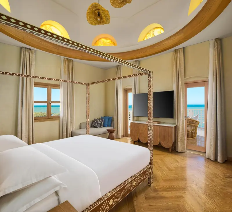 Une chambre avec un grand lit à baldaquin et vue sur la mer.