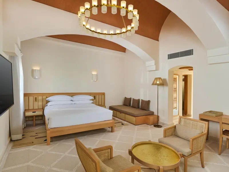 Une chambre lumineuse avec un grand lit et un coin salon.