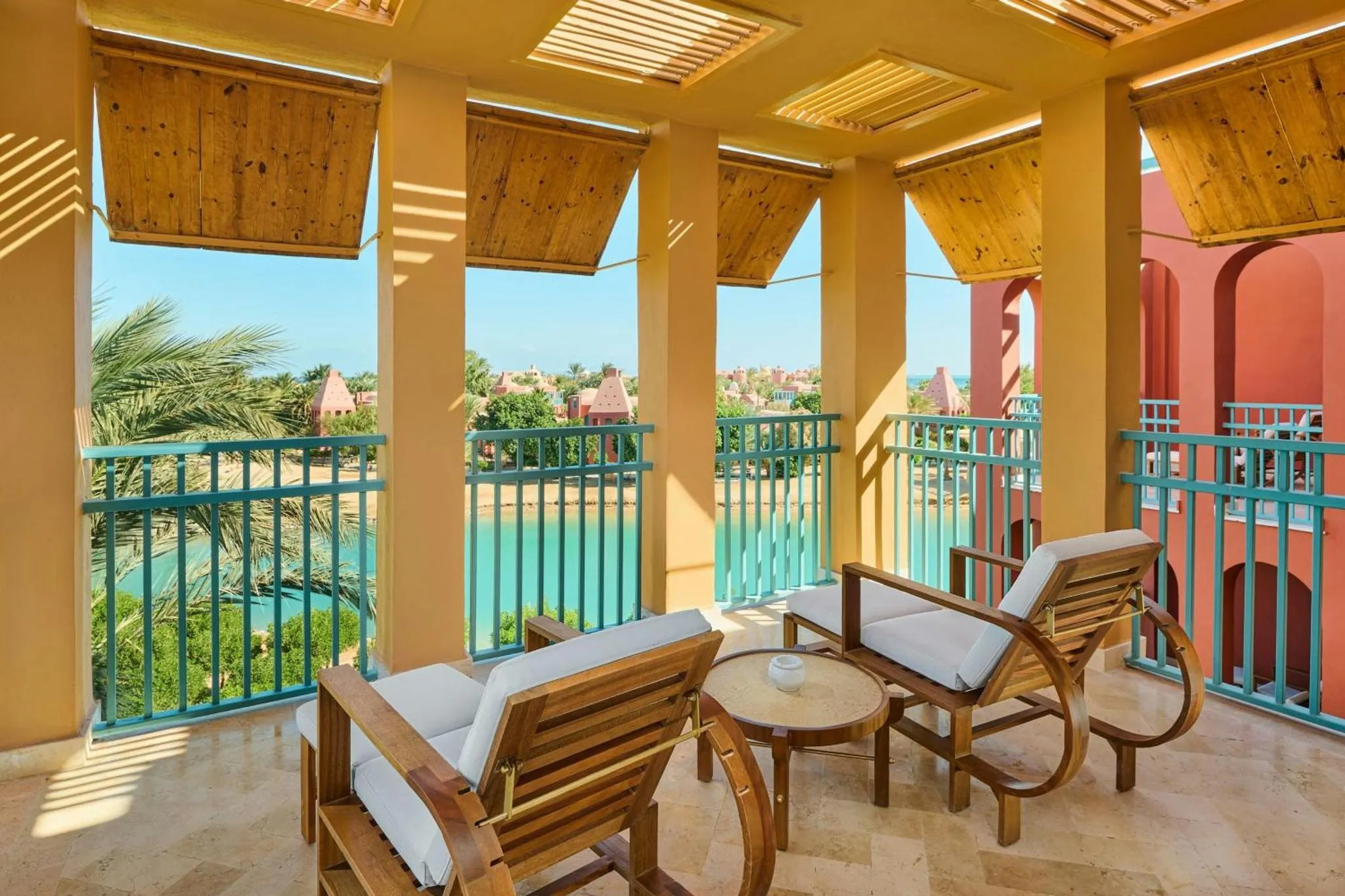 Terrasse ombragée avec mobilier de jardin et vue sur la mer.