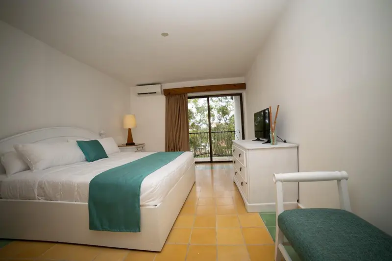 Une chambre lumineuse avec un grand lit et une vue sur la végétation.