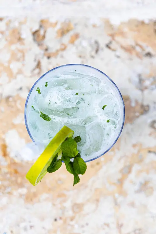 Boisson rafraîchissante dans un verre bleu avec une tranche de citron vert et de la menthe.