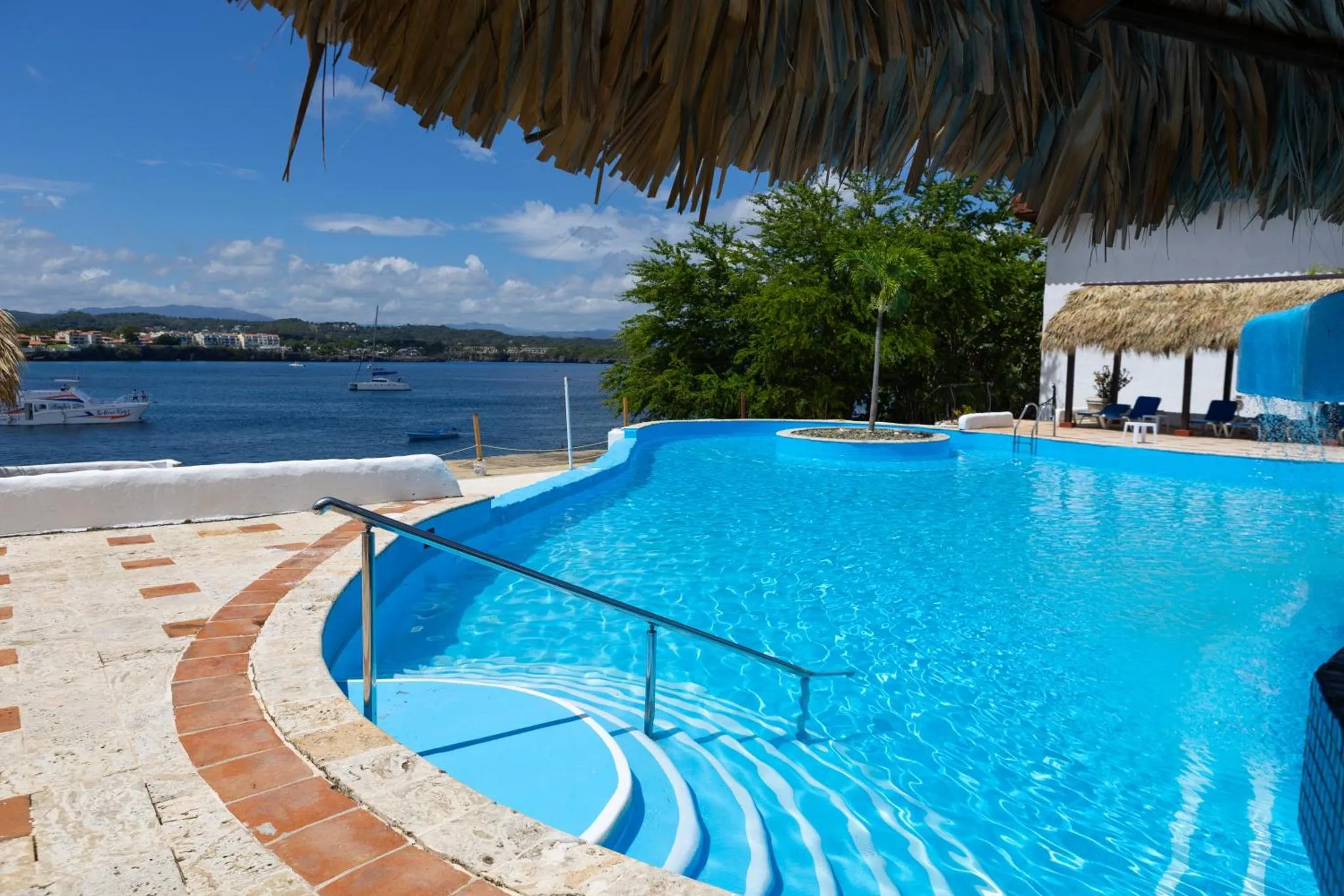 Piscine bleue avec bord incurvé et vue sur la mer.