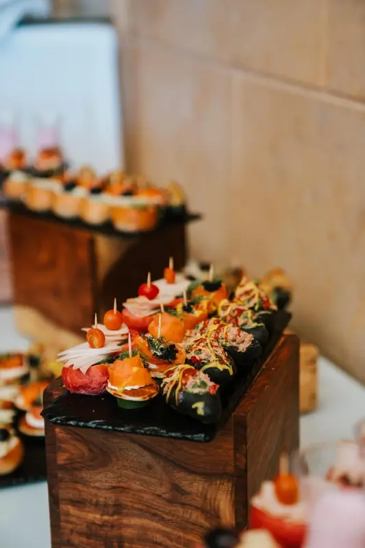 Assortiment de bouchées apéritives colorées présentées sur des plateaux en bois.