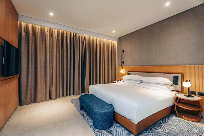 Une chambre moderne avec un grand lit et des rideaux beiges.