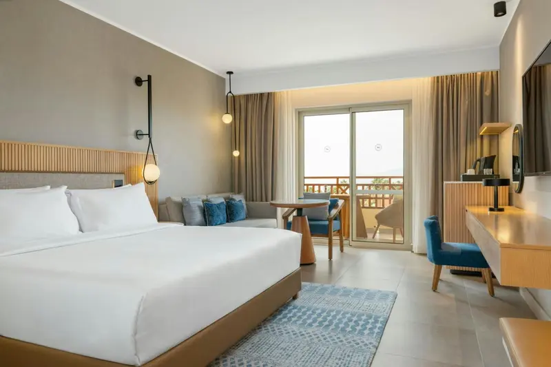Une chambre lumineuse avec un grand lit et un accès à un balcon.