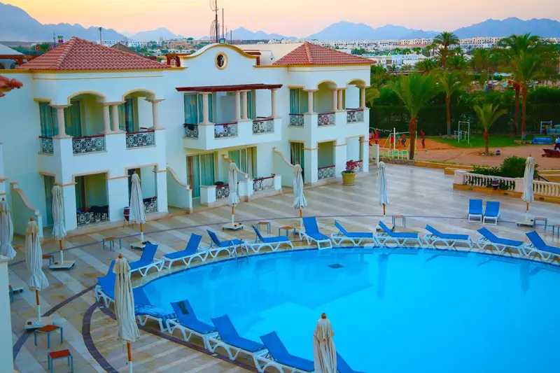 Bâtiment blanc à deux étages surplombant une piscine et un espace de détente.