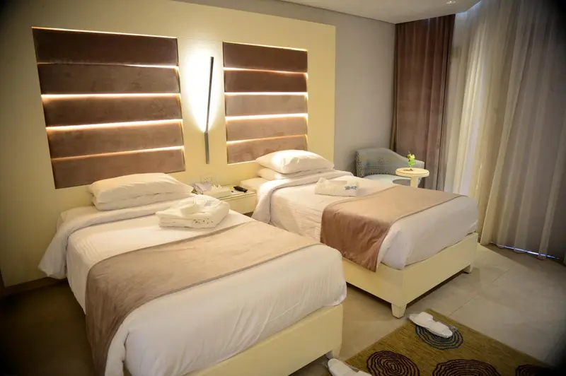 Une chambre lumineuse avec deux lits simples et une décoration neutre.