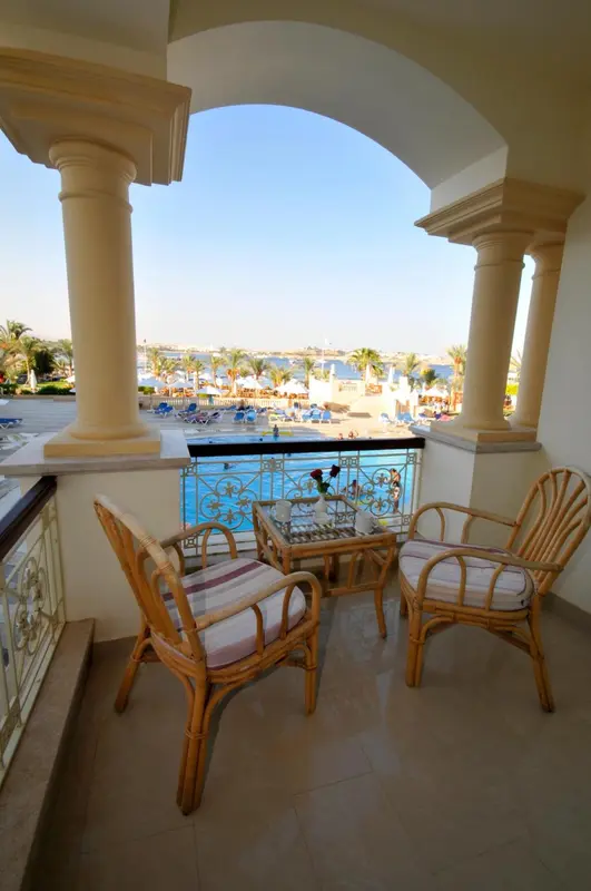 Terrasse avec mobilier en rotin donnant sur une piscine et la mer.