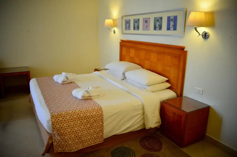Une chambre lumineuse avec un grand lit recouvert d'une courtepointe.