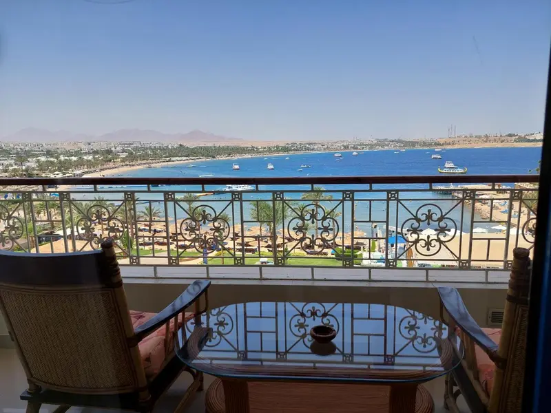 Vue d'un balcon avec mobilier donnant sur une plage et la mer.