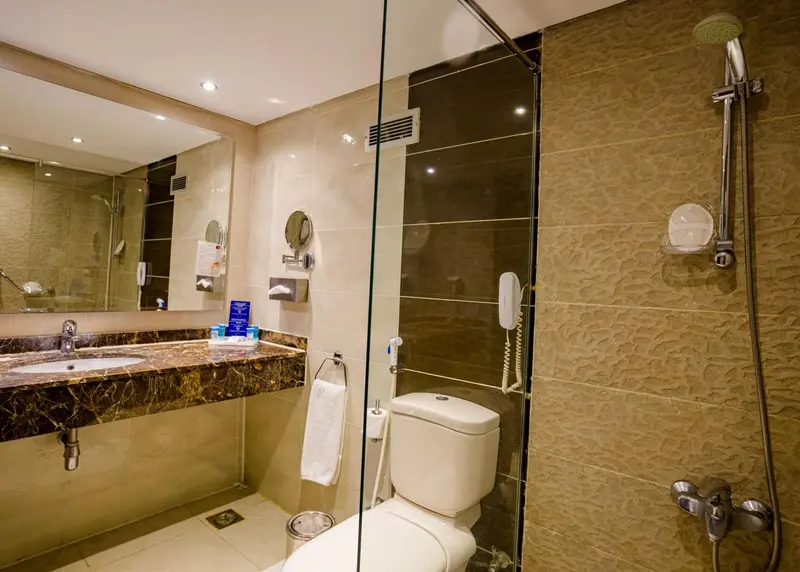 Une salle de bain claire avec douche à l'italienne et lavabo en marbre.