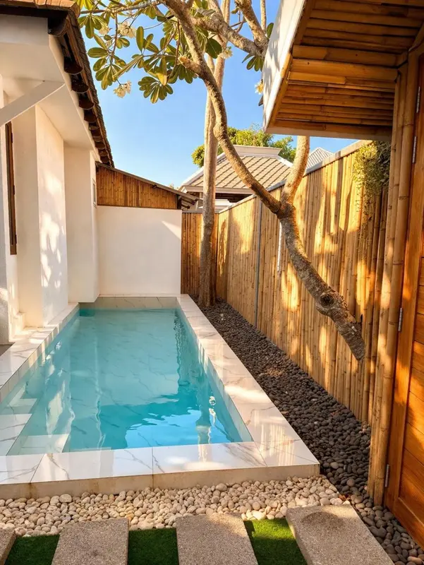 Petite piscine rectangulaire dans une cour pavée.