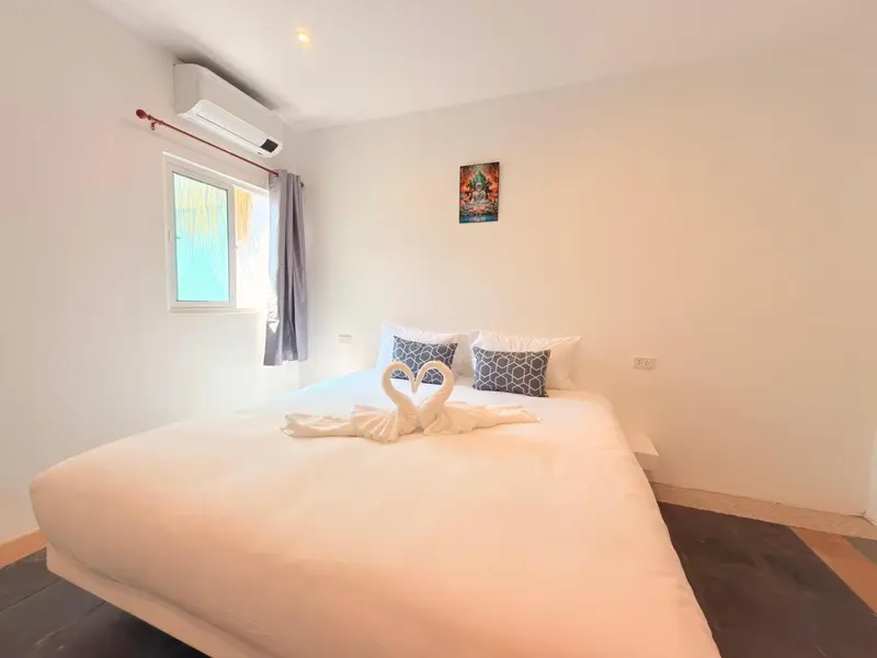 Une chambre lumineuse avec un grand lit décoré de serviettes en forme de cygnes.