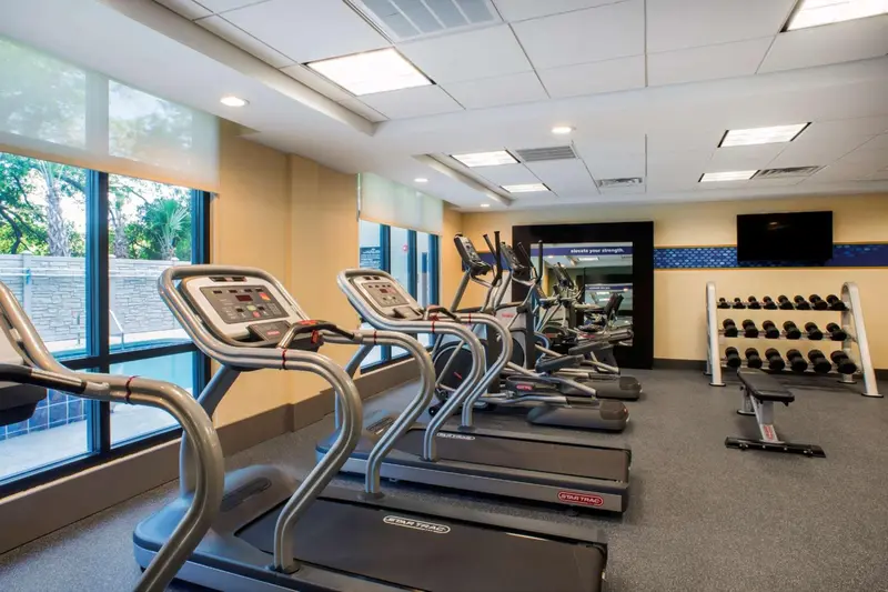 Une salle de sport lumineuse avec des équipements de cardio et de musculation.