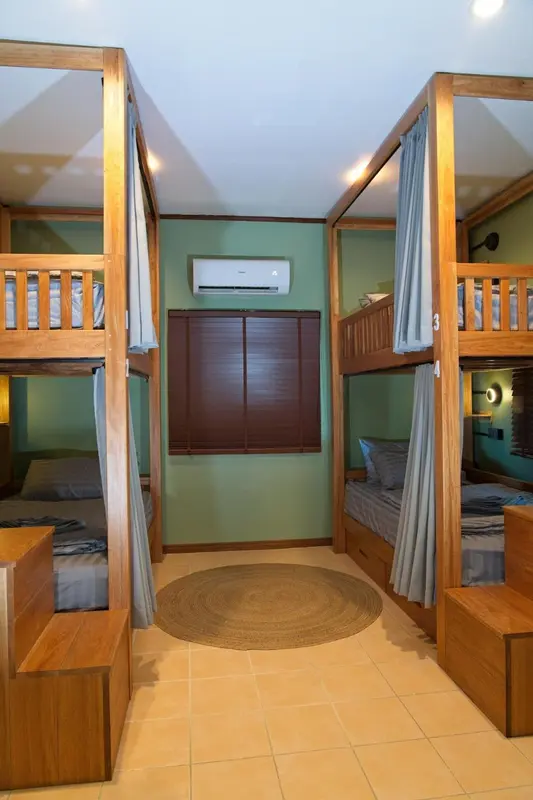 Lits superposés en bois clair dans une chambre aux murs verts.