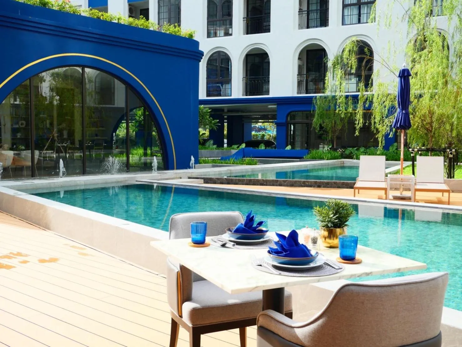 Une table est dressée au bord d'une piscine avec des chaises et de la vaisselle.