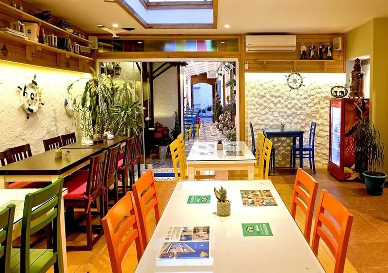 Une salle de restaurant lumineuse avec des tables colorées et une décoration murale.