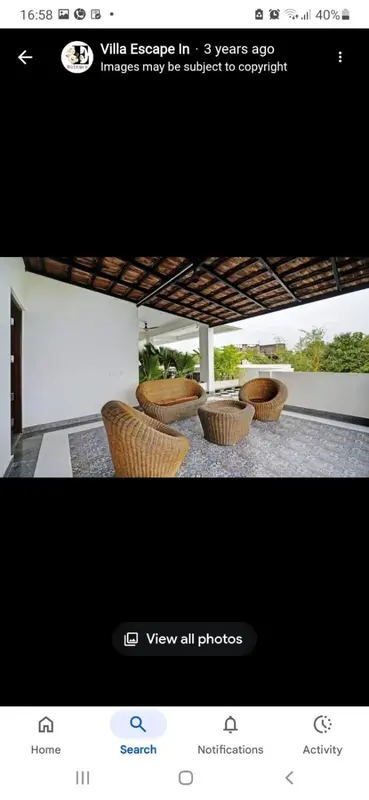 Espace de détente extérieur avec mobilier en rotin sous une pergola.