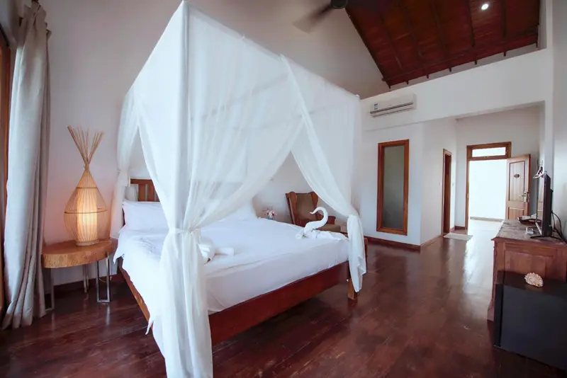 Une chambre lumineuse avec un lit à baldaquin et une décoration soignée.