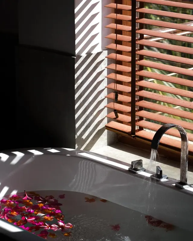 Une baignoire remplie d'eau et de fleurs, avec un robinet chromé.
