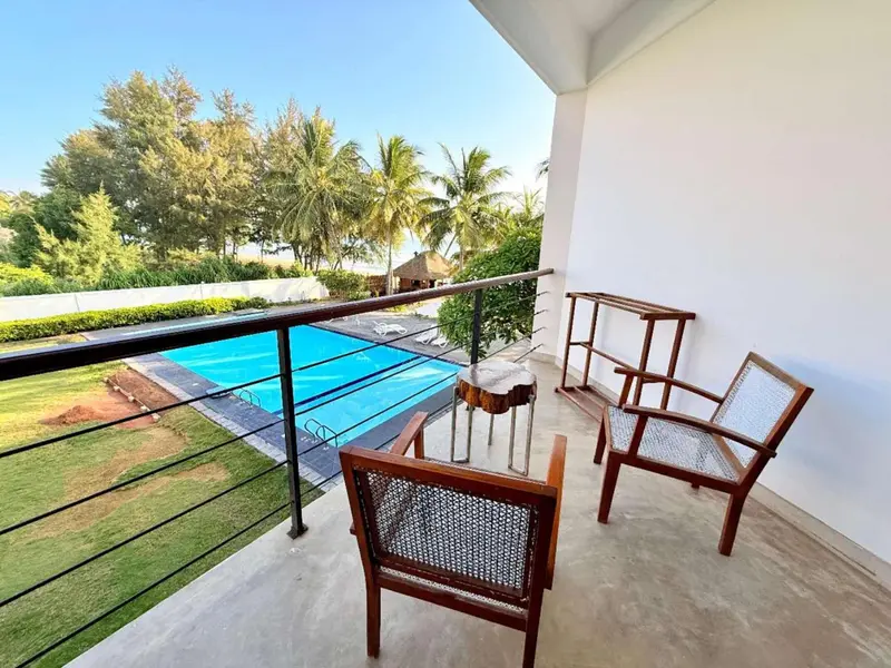 Terrasse avec mobilier en bois donnant sur une piscine et une végétation luxuriante.