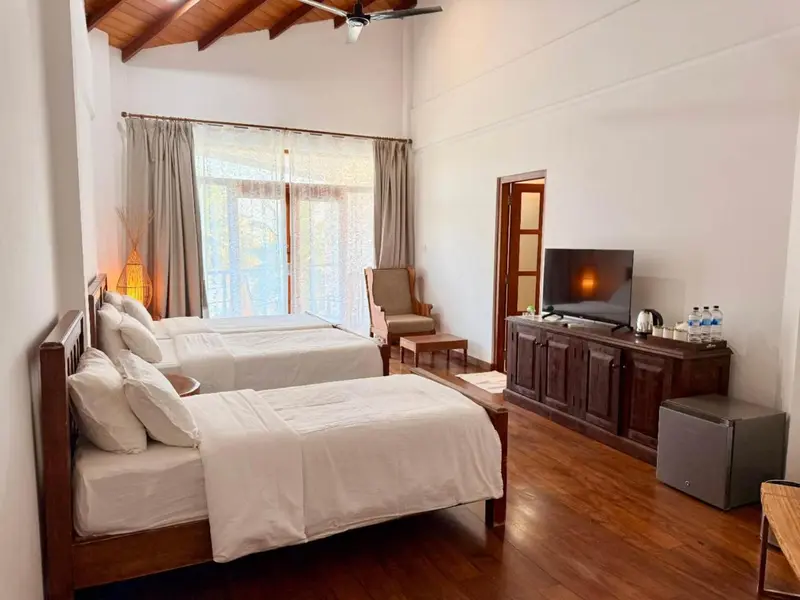 Une chambre lumineuse avec deux lits simples et un meuble bas en bois.