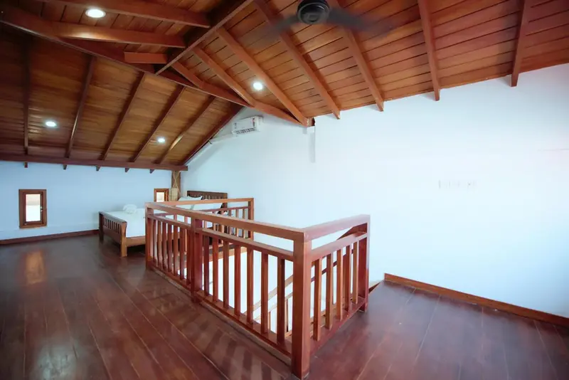 Une chambre mansardée avec deux lits simples et une rambarde en bois.