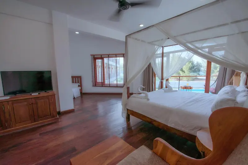 Une chambre spacieuse avec un lit à baldaquin et une télévision à écran plat.
