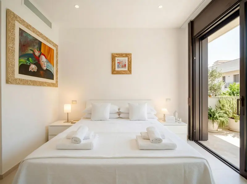 Une chambre lumineuse avec un grand lit et un accès à une terrasse.