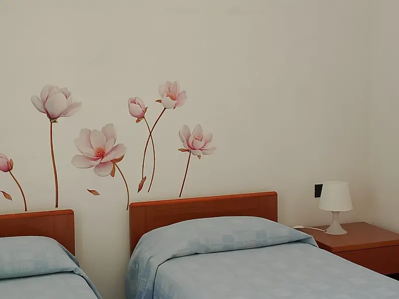 Une chambre avec un lit et une décoration florale au mur.
