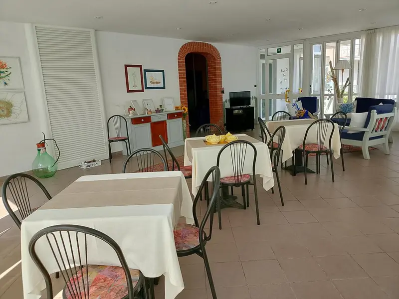 Une salle lumineuse avec des tables nappées et des chaises.