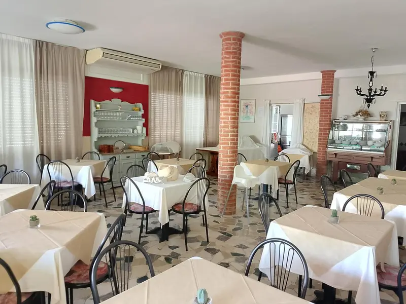 Une salle lumineuse avec des tables nappées et des chaises.