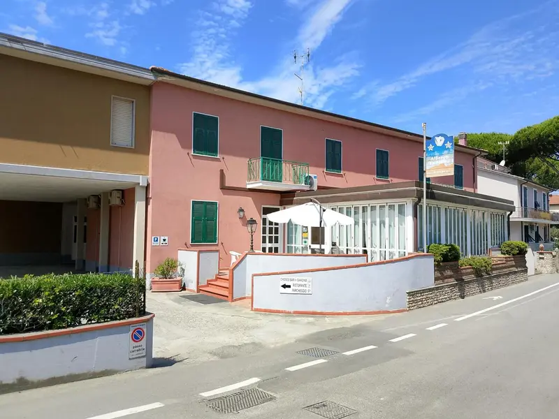 Façade d'un bâtiment rose et blanc avec des fenêtres et un auvent.
