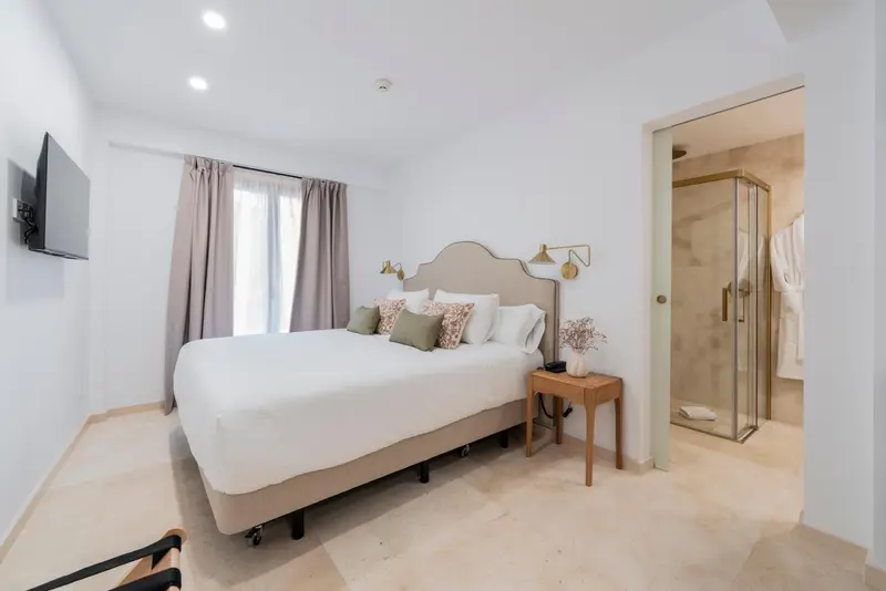 Une chambre lumineuse avec un grand lit et une salle de bain attenante.