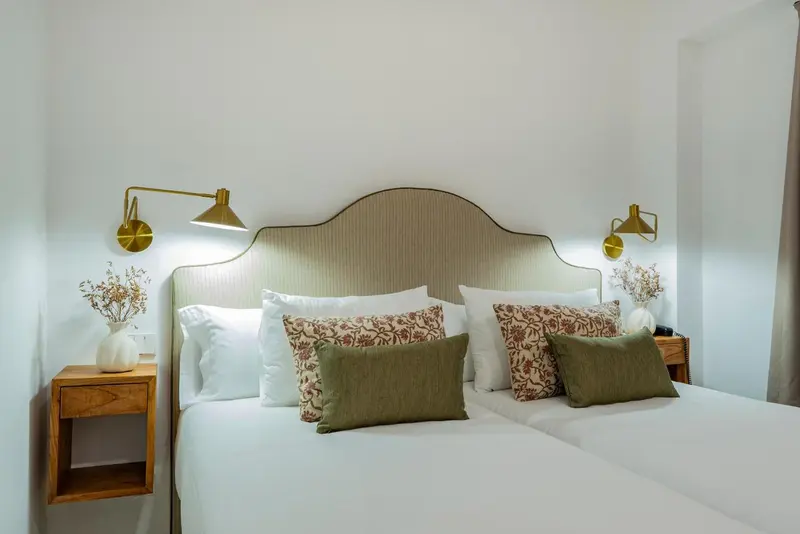 Lit double avec oreillers et chevets dans une chambre lumineuse.