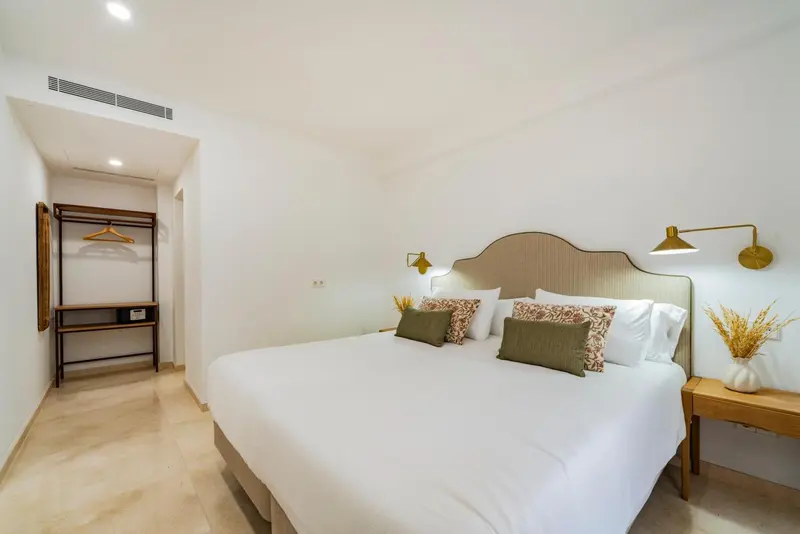 Une chambre lumineuse avec un grand lit recouvert de coussins.