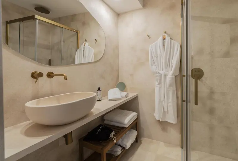 Une salle de bain moderne avec un lavabo blanc et des peignoirs.