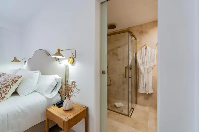 Une chambre lumineuse avec un lit et une douche à l'italienne.