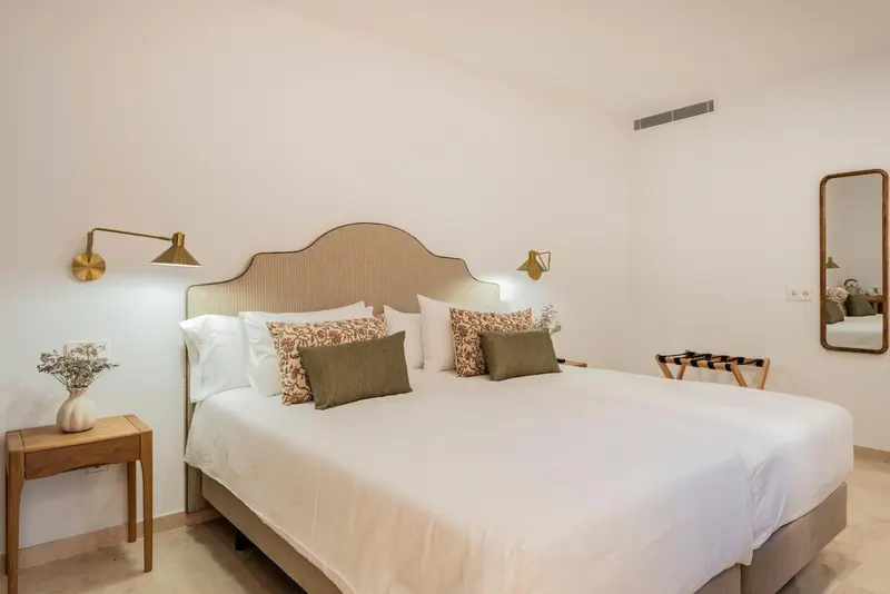 Une chambre lumineuse avec un grand lit recouvert de linge blanc et de coussins.