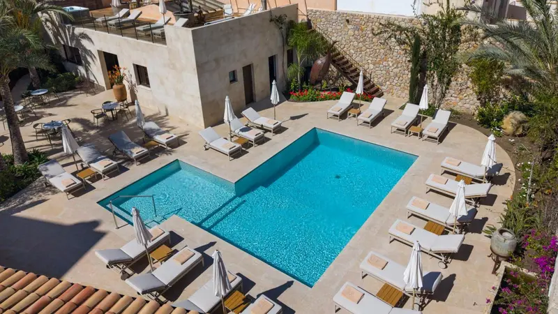 Transats blancs disposés autour d'une piscine rectangulaire turquoise.