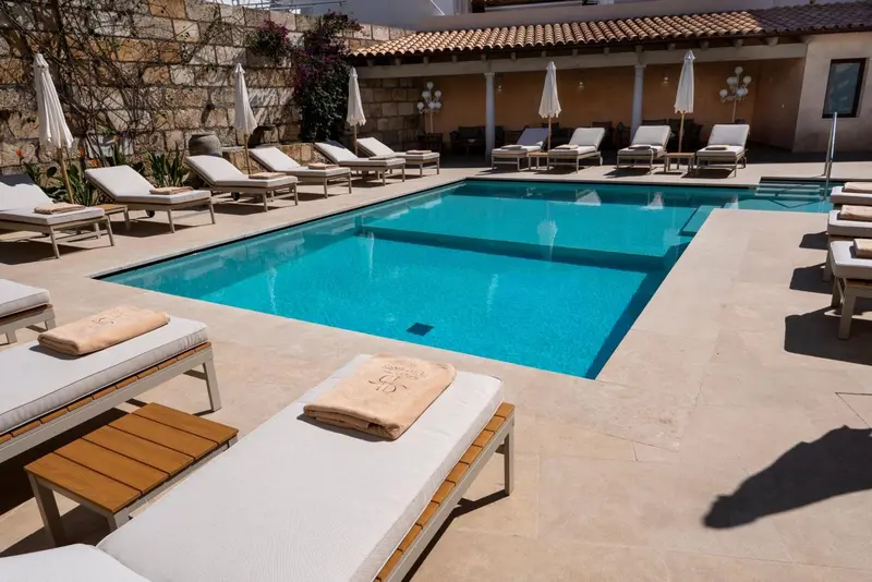 Transats blancs disposés autour d'une piscine rectangulaire carrelée.