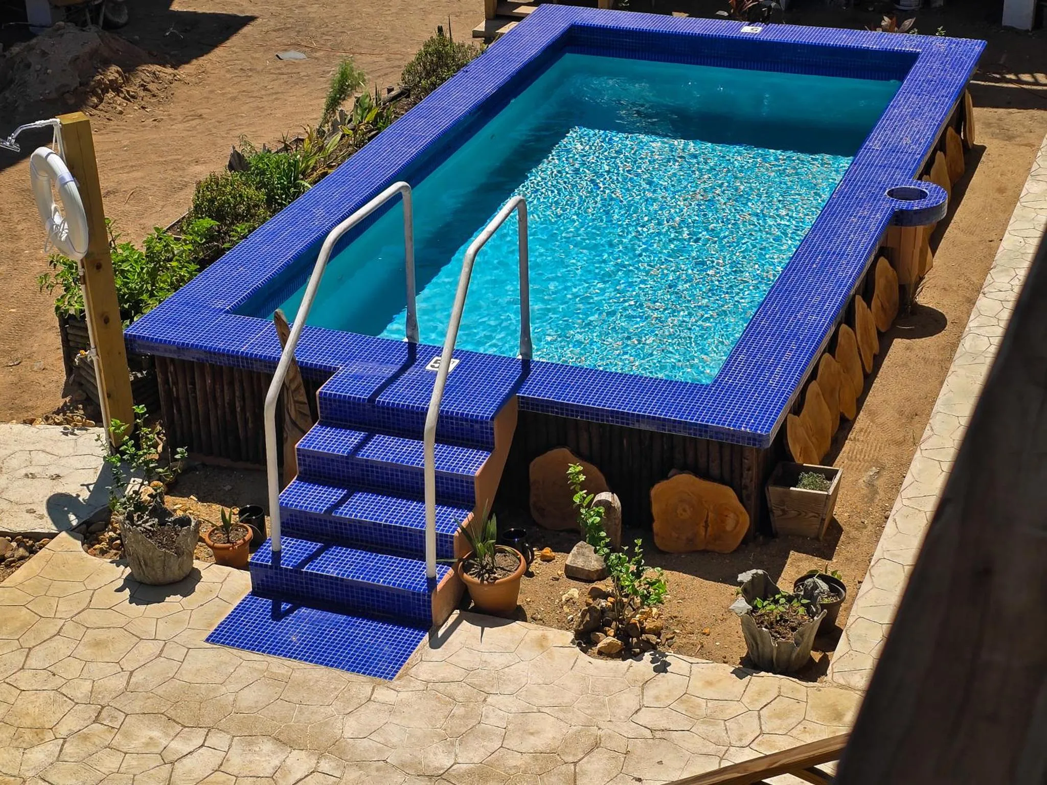 Une piscine rectangulaire bleue entourée d'une terrasse carrelée.