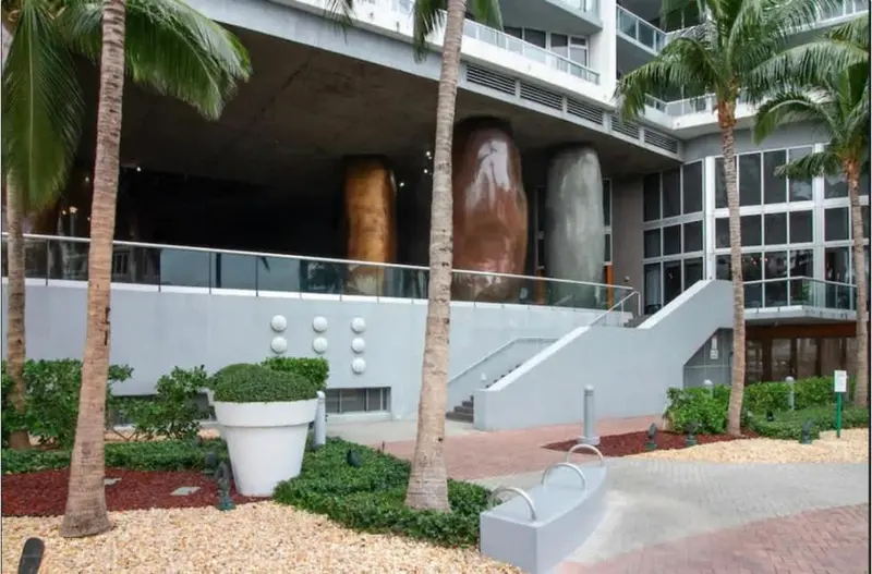 Façade d'un bâtiment moderne avec des éléments architecturaux organiques et une végétation tropicale.