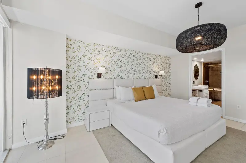 Une chambre lumineuse avec un grand lit recouvert de coussins.
